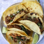 crispy carnitas tacos on plate with extra tortillas