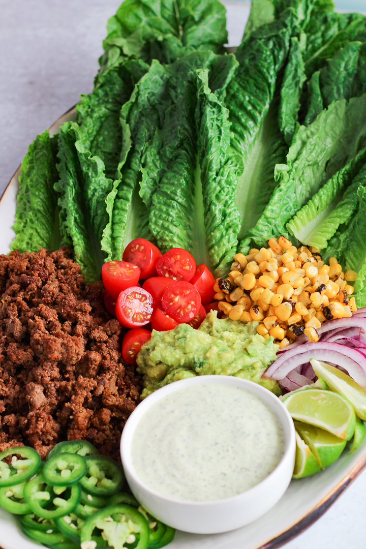 Platter with lettuce, roasted corn, tomatoes and ground beef with bowl of ranch dressing