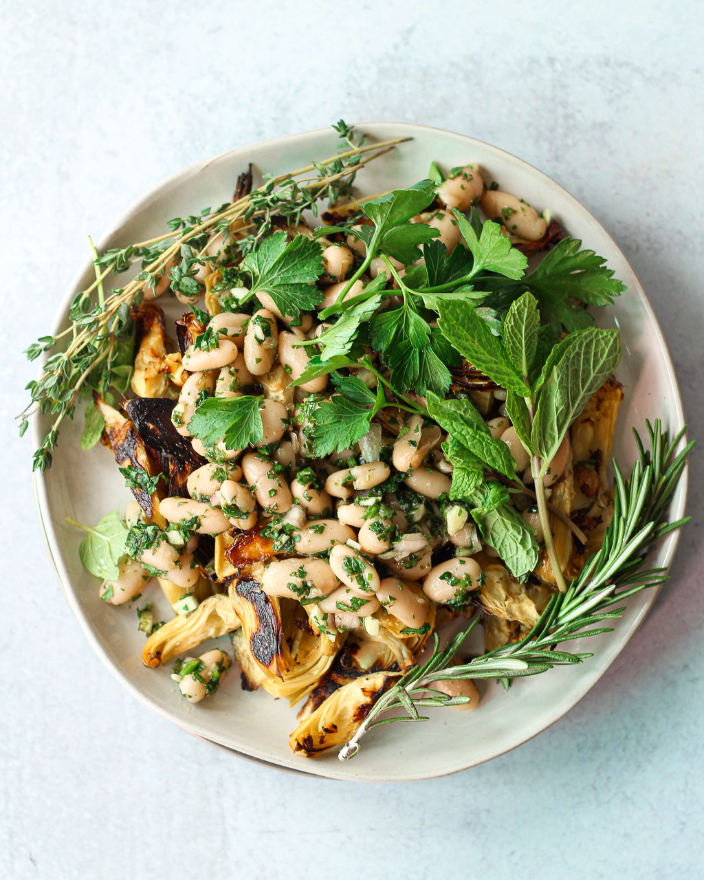 roasted artichoke bean salad on plate with herbs