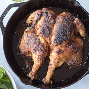 peruvian style chicken on pan with spicy green sauce on side