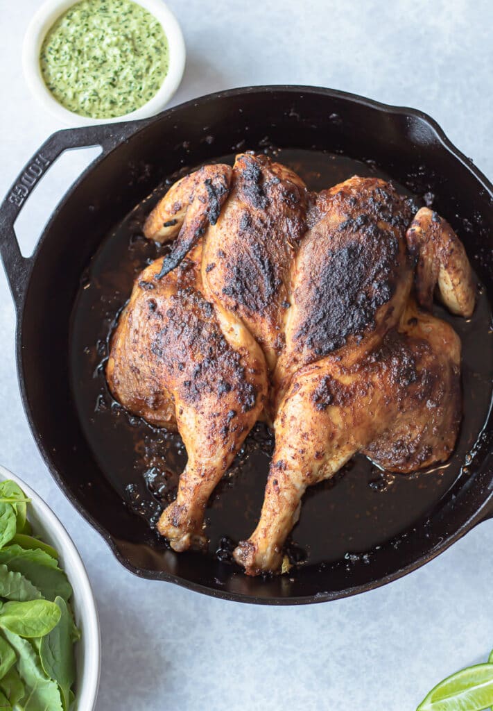 peruvian style chicken on pan with spicy green sauce on side