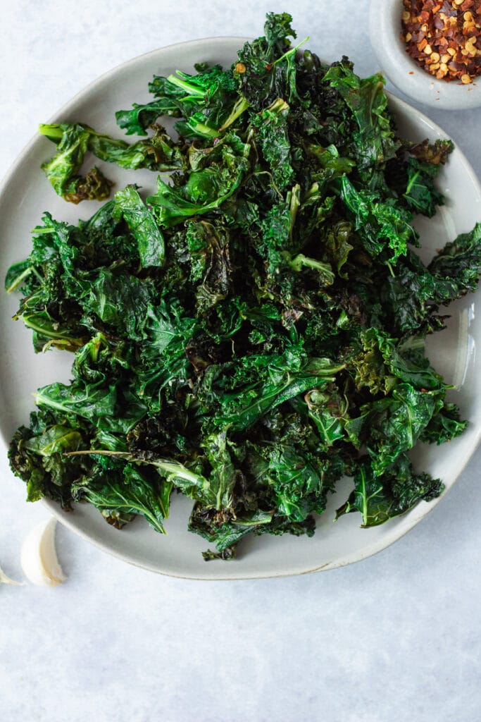 plate of sautéed kale with small bowl of pepper flakes