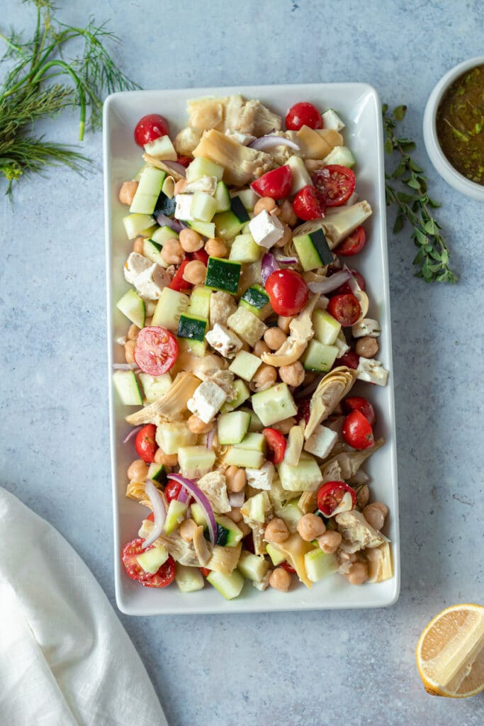 platter of greek salad with marinated feta and dressing on side