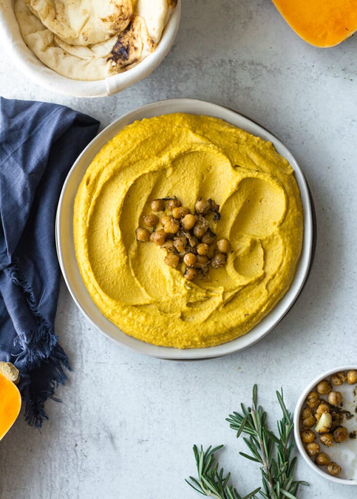 hummus on plate surrounded by butternut squash, extra chickpeas and naan