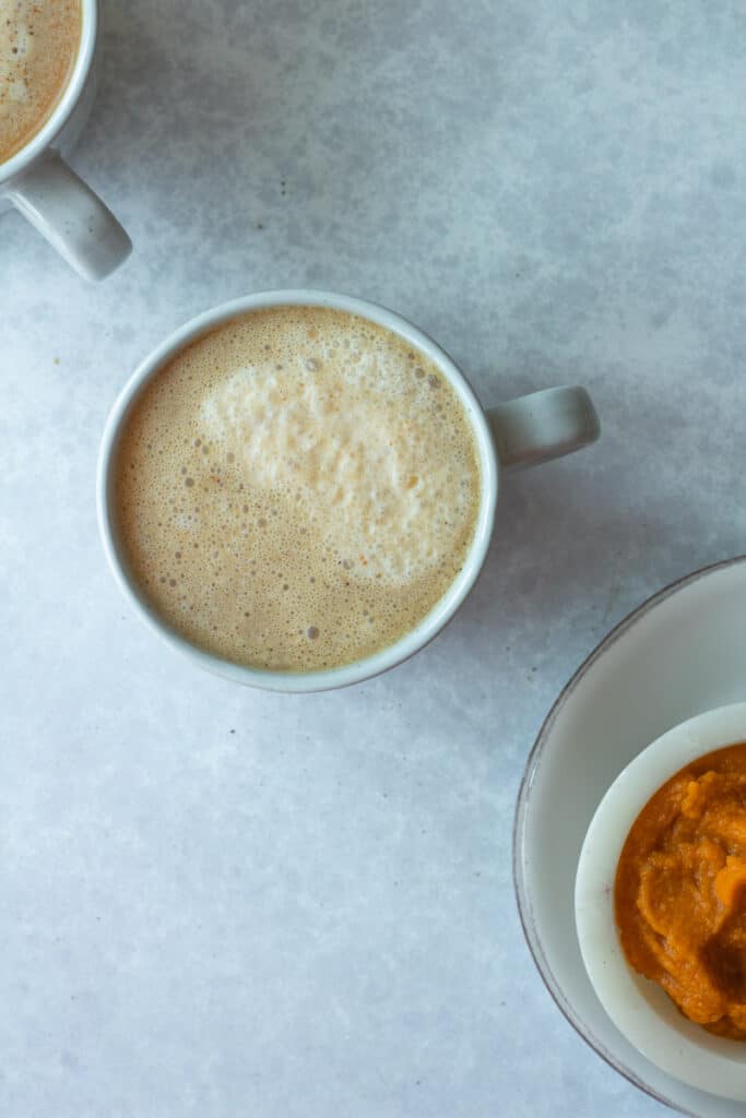 overhead of pumpkin cream coffee with pumpkin in small bowl