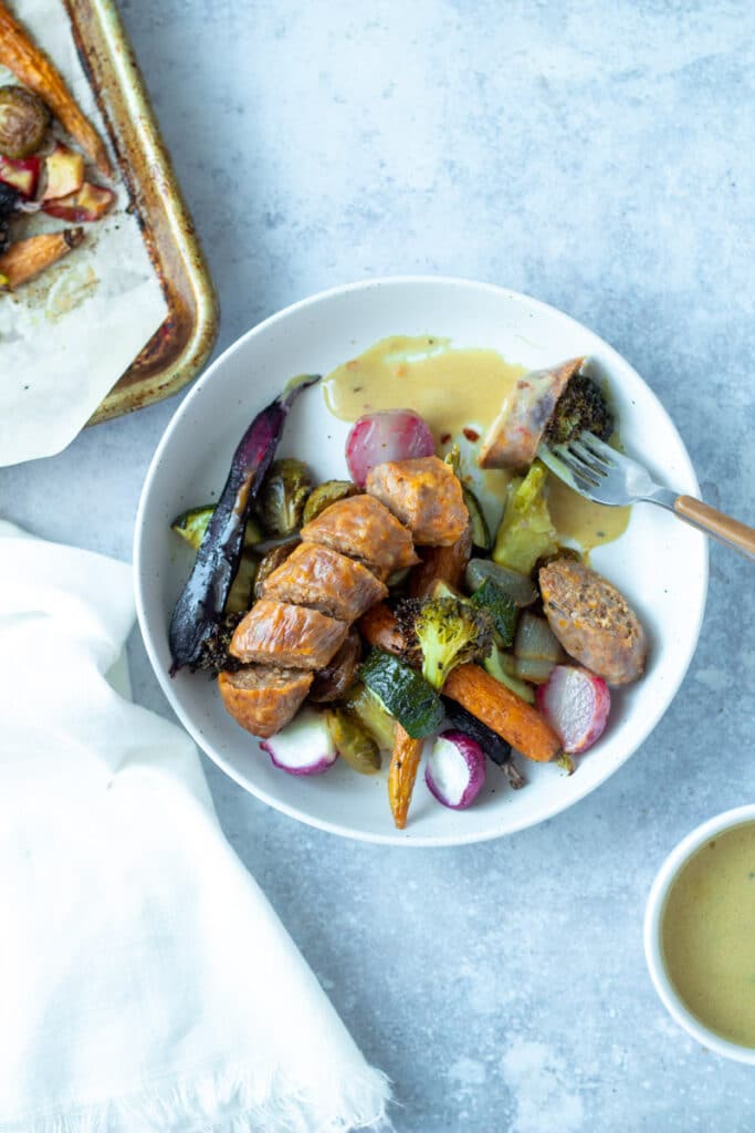 sausage and vegetables in plate with sheet pan in corner