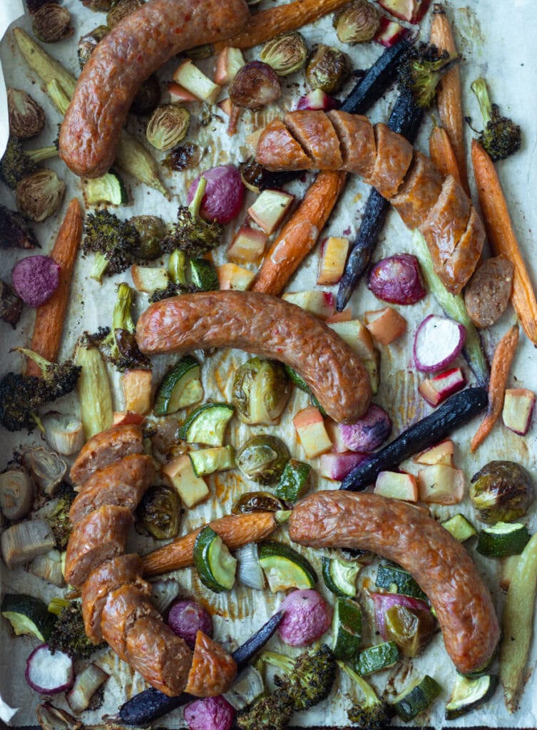 cut and whole sausage on sheet pan with vegetables