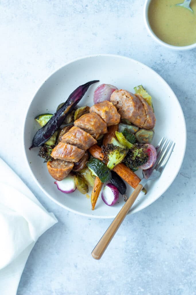 sausage and vegetables on plate, with dressing in bowl on side