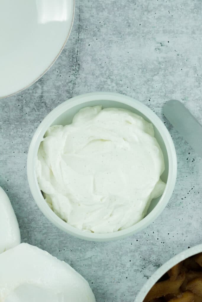 cardamom whipped cream in small bowl next to pavlova base