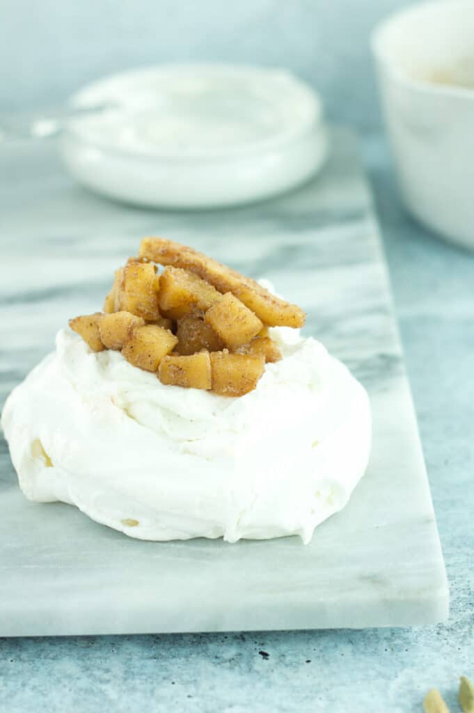 apple pie pavlova with apples and whip cream in background