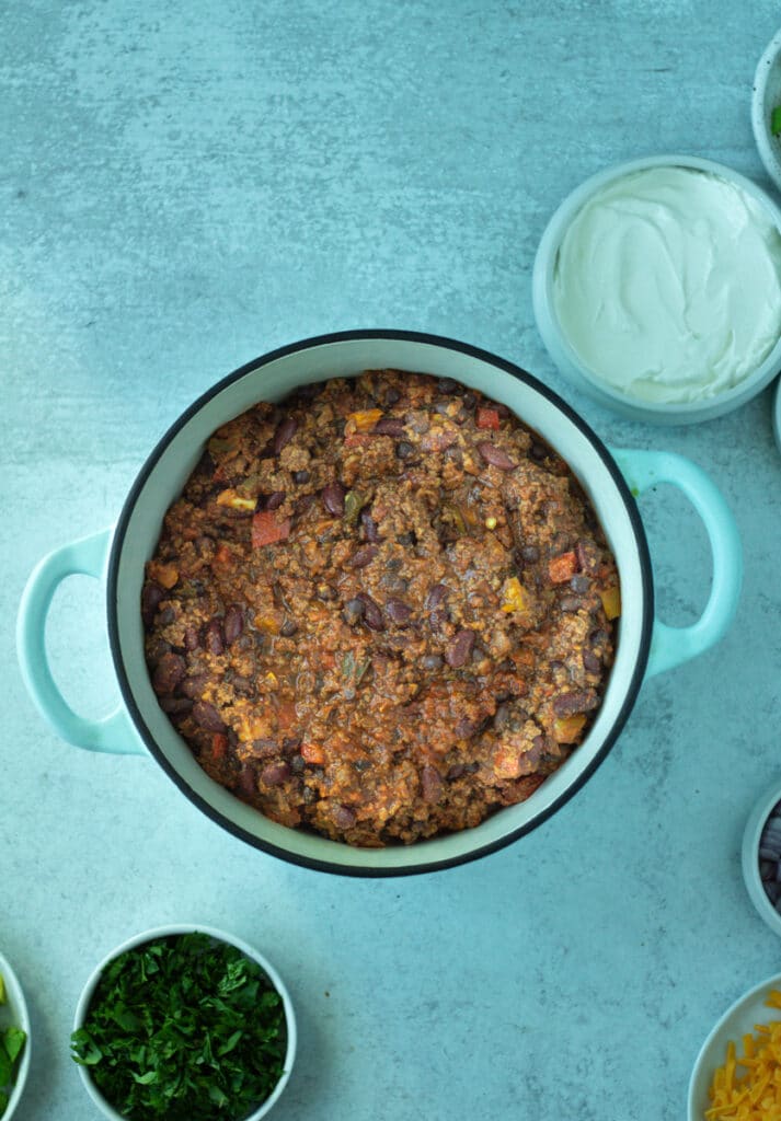 Chili in pot with toppings in small bowls.