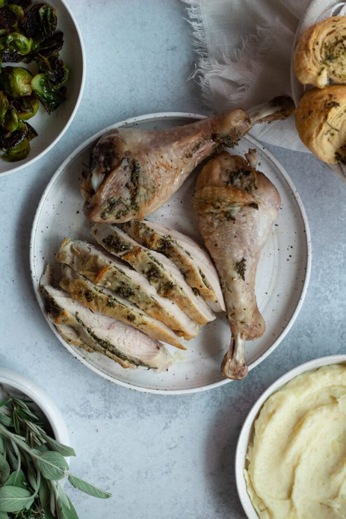 carved turkey on plate surrounded by sides and rolls