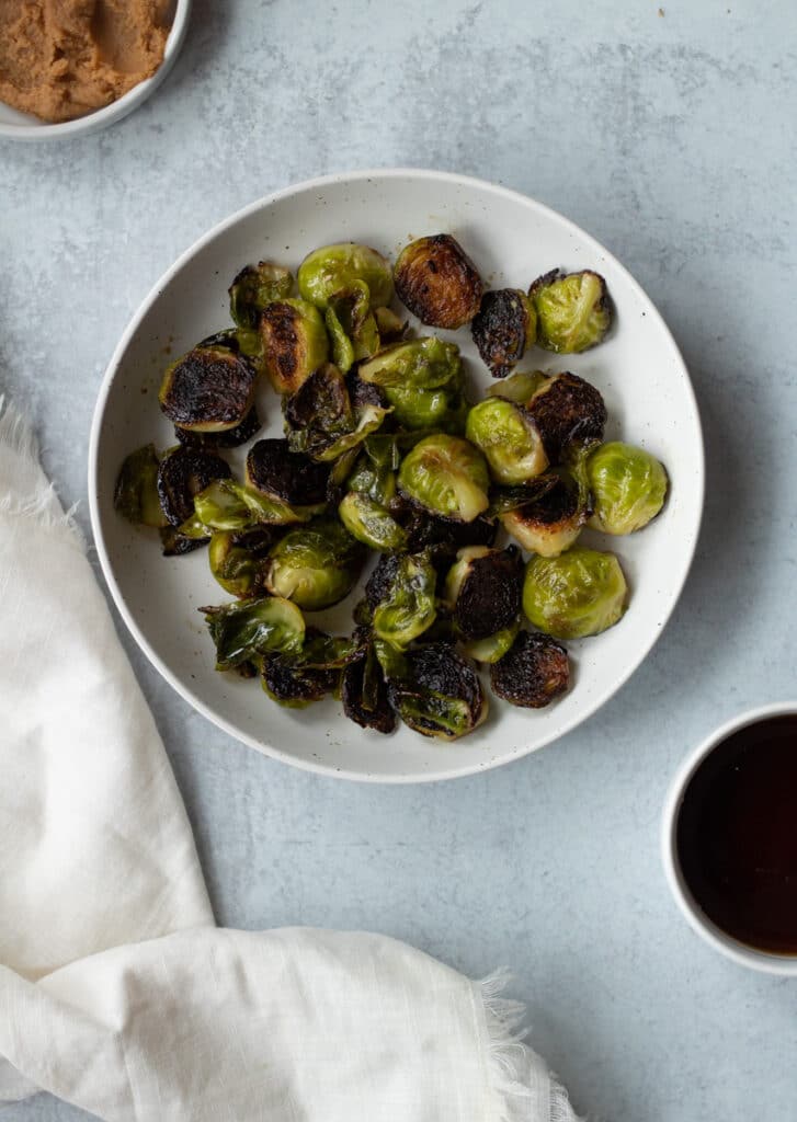 plate of brussels sprouts with small bowls of maple syrup and white miso
