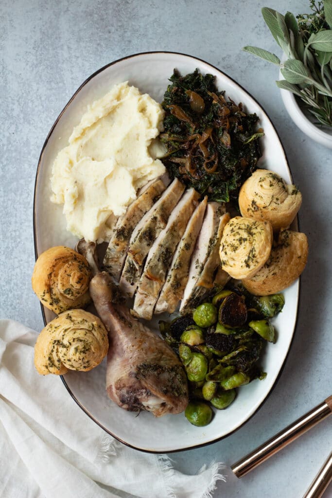 platter of thanksgiving food for two with turkey, mashed potatoes, kale, brussels sprouts