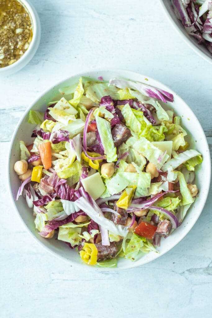 italian chopped salad mixed together in bowl with dressing