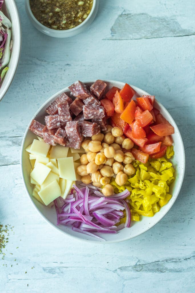 salami, peppers, onions, cheese and tomatoes in bowl for italian chopped salad