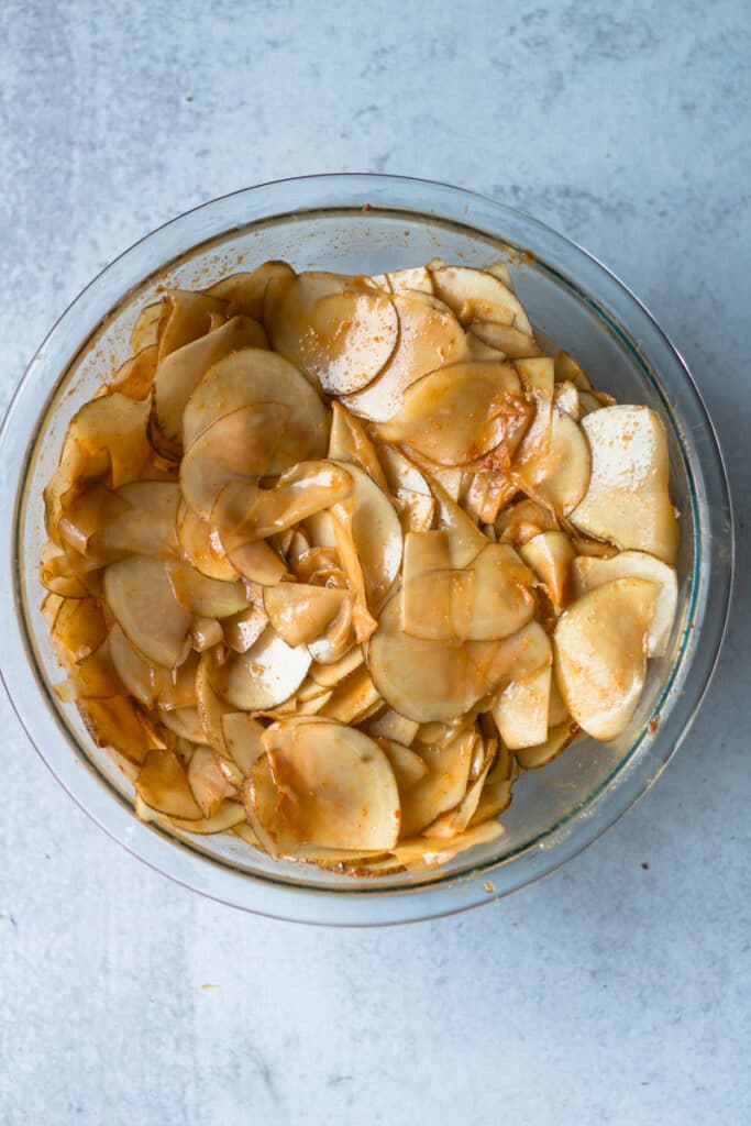 raw potato slices in bowl with seasonings