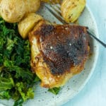 close up shot of chicken thigh with hot honey on plate with side dishes and small bowl of seasoning on side