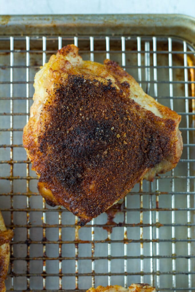 Close up shot of roasted chicken thigh on wire rack