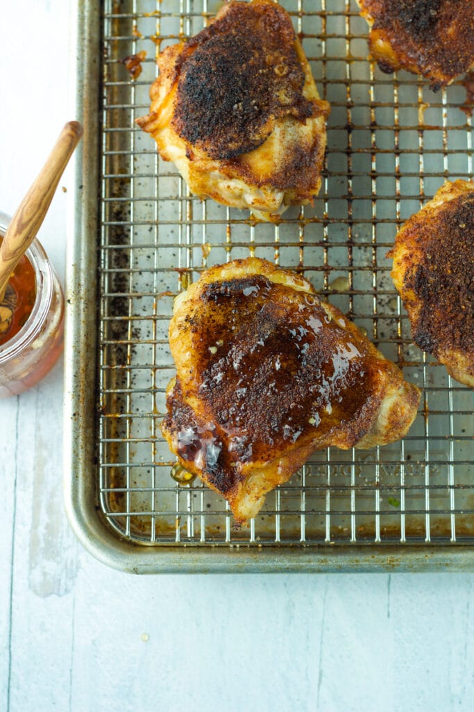 Roasted chicken thighs on wire pan drizzled with hot honey