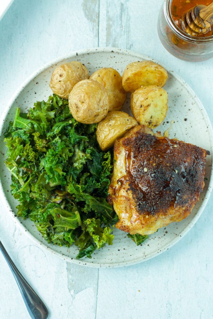 plated chicken thigh with hot honey and fork on the side