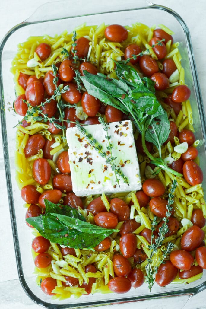raw ingredients for tomato and feta pasta in glass baking dish