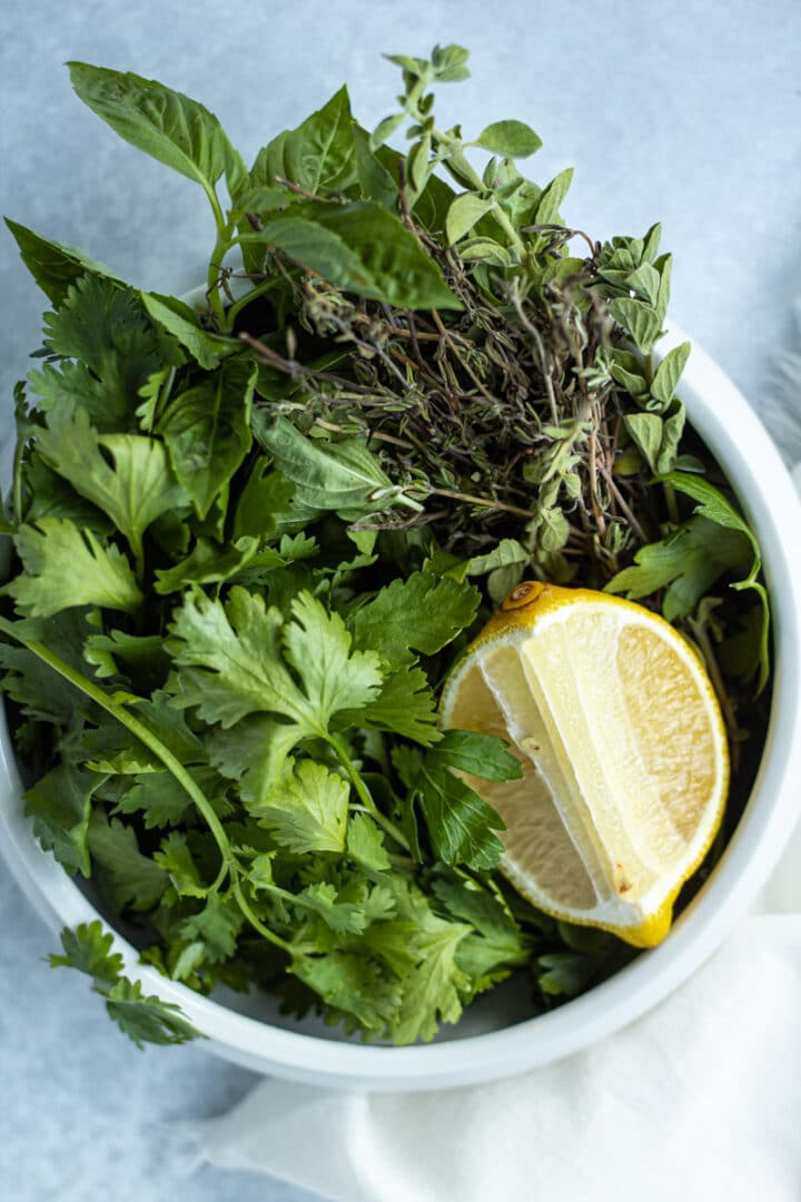 Bowl of herbs including basil, oregano and lemon