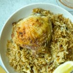 closeup shot of garlic chicken and rice on plate with lemon wedge