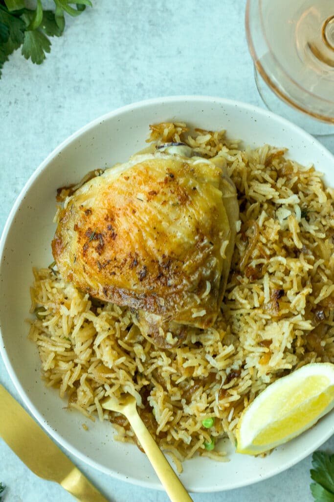 closeup shot of garlic chicken and rice on plate with lemon wedge