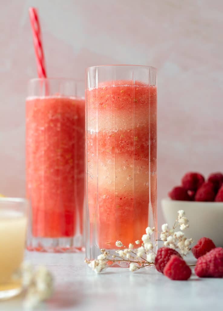 Two glass of raspberry limoncello frosé with flowers and raspberries