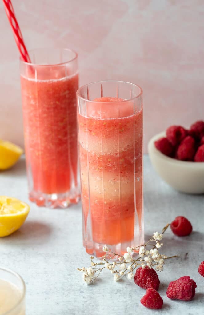 glasses with frosé surrounded by flowers, a small bowl of raspberries and a small glass of limoncello