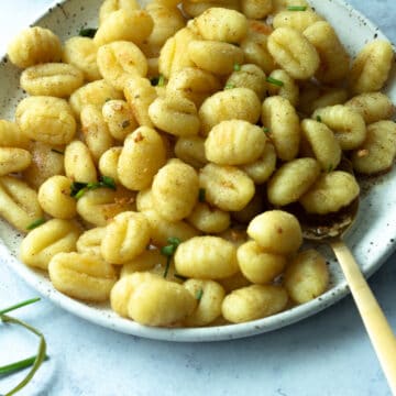 Roasted gnocchi on plate with large serving spoon