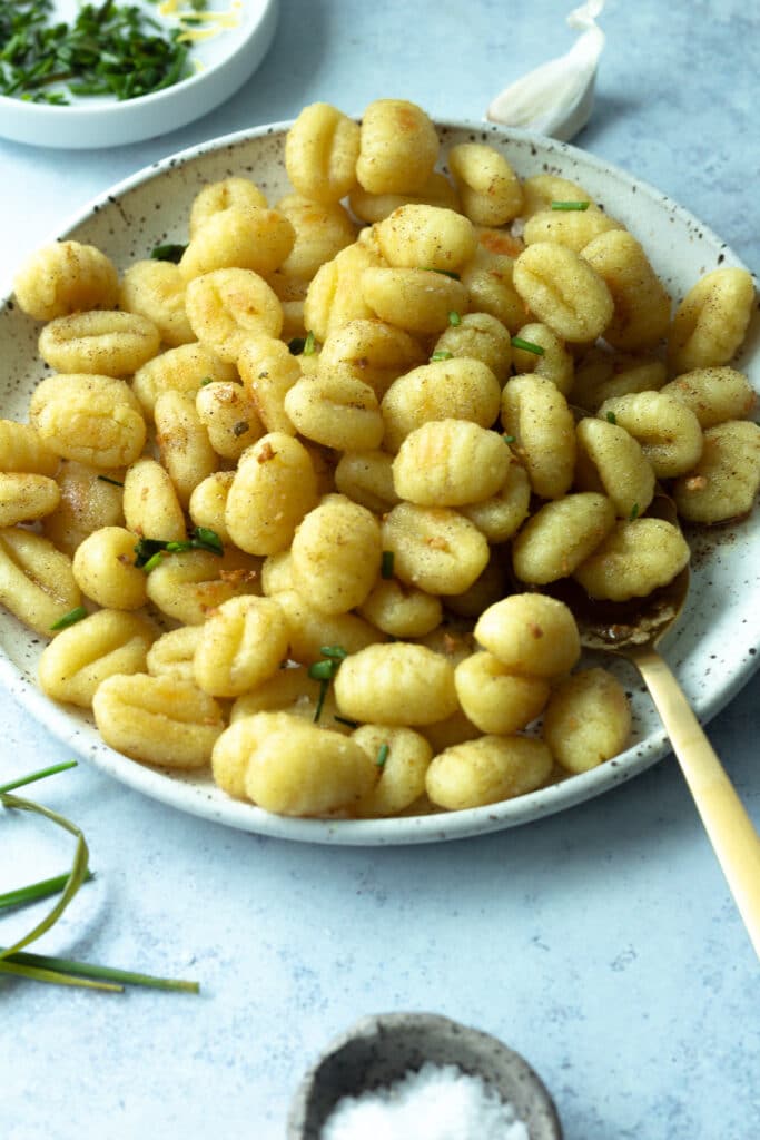 Roasted gnocchi on plate with large serving spoon