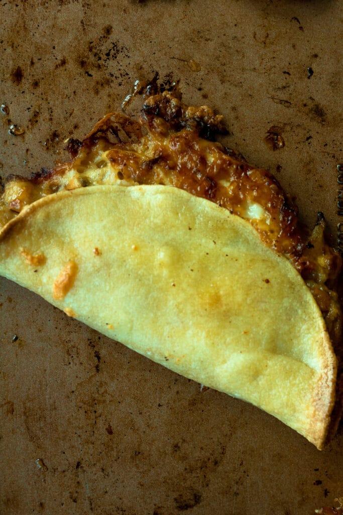 close up shot of baked chicken taco on baking sheet