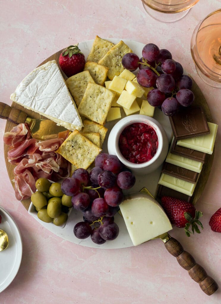 board with cheese, chocolate, olives, strawberry jam and crackers