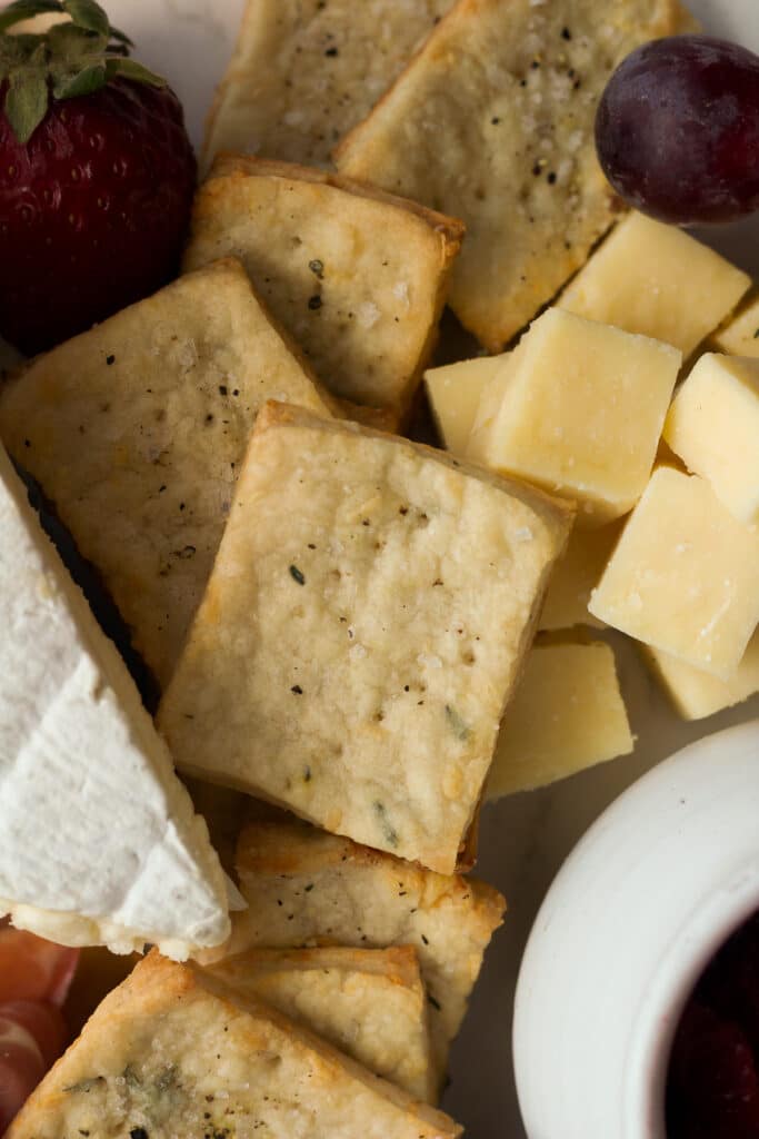 close up shot of parmesan thyme crackers next to cheese cubes