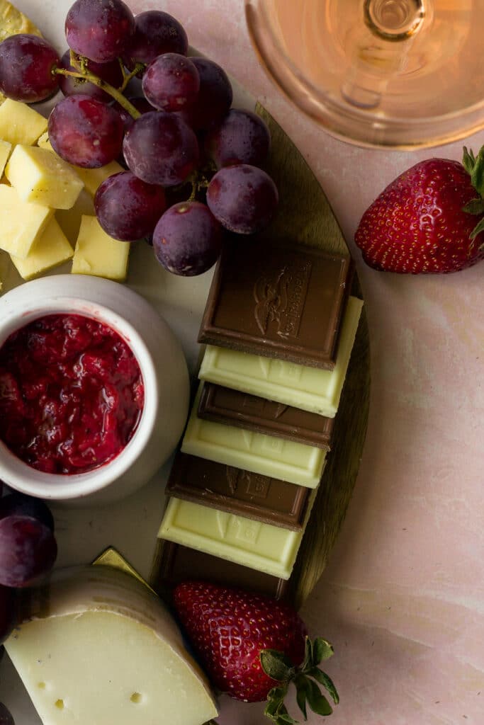 close up shot of chocolate bars and fruit on rose cheese board
