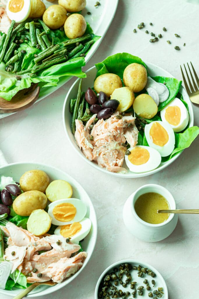 finished niçoise salads with dressing and fried capers on side