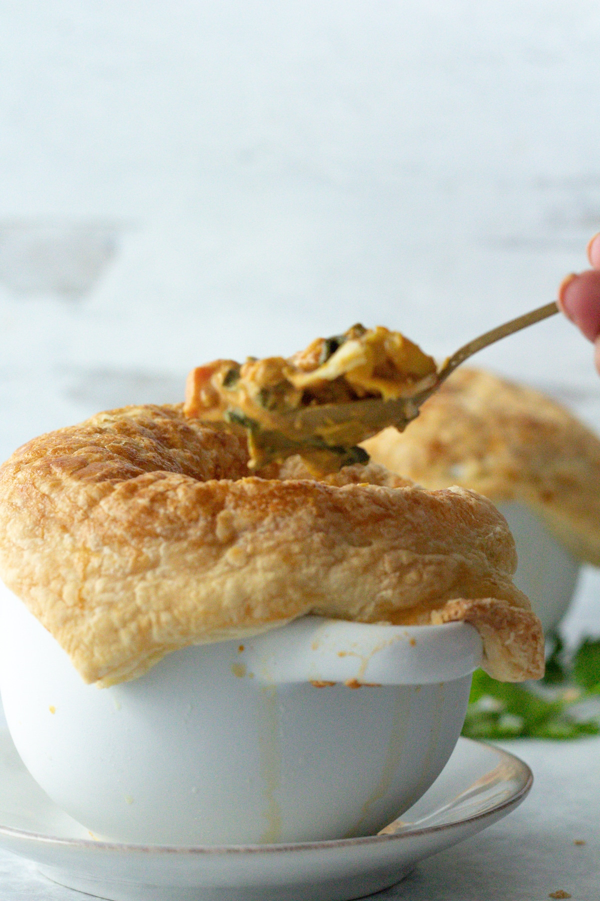 Hand with spoon scooping filling from pot pie.