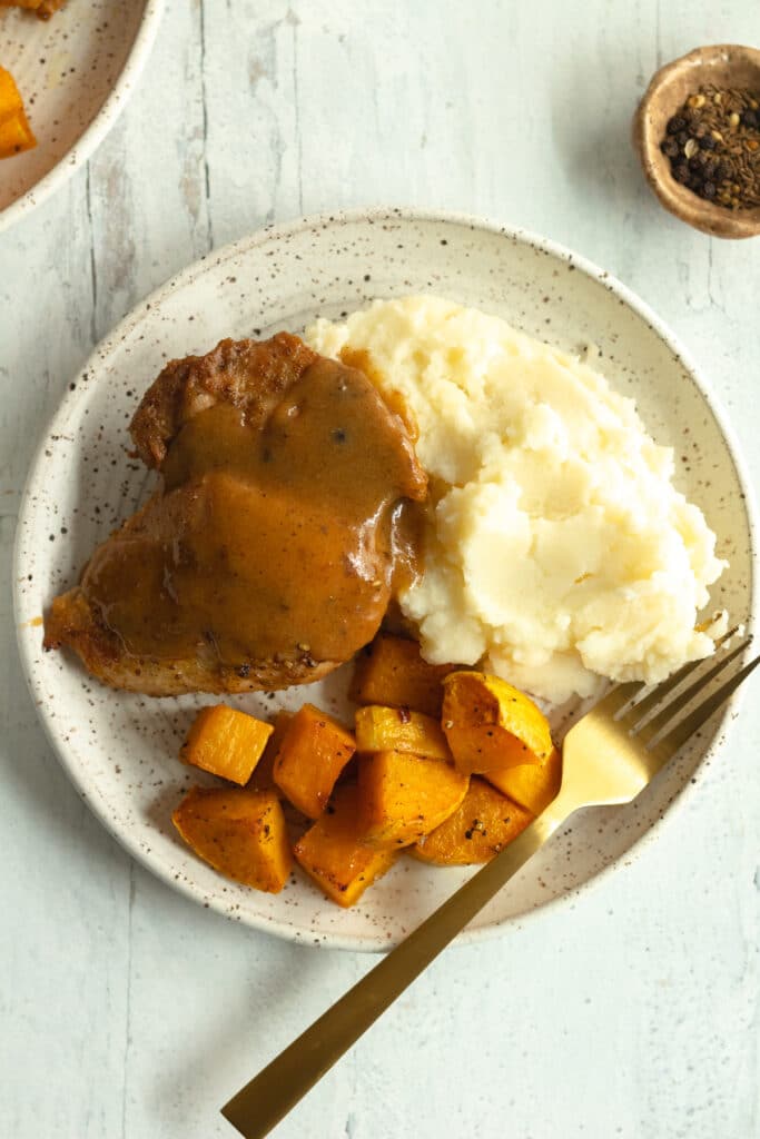 dinner plate of apple cider chicken with roasted squash and mashed potatoes and fork