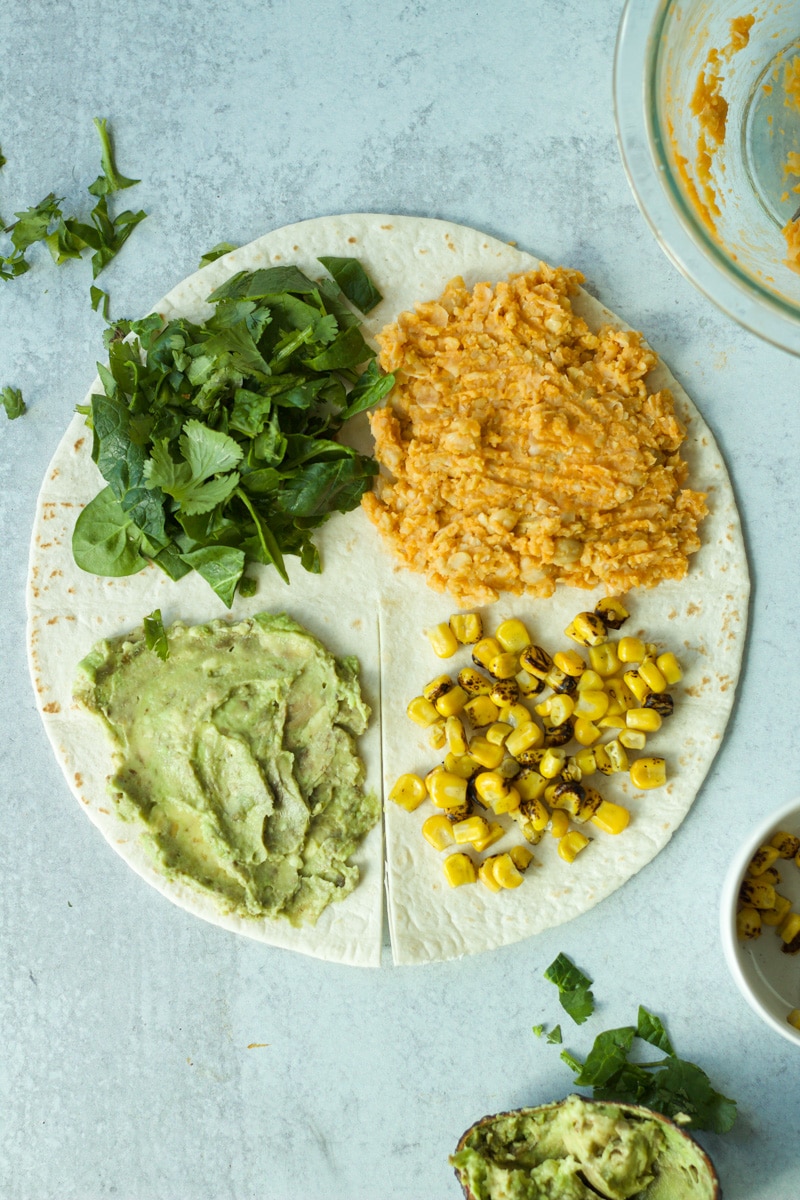 Buffalo chickpea wrap with ingredients on each quarter, before wrapping.