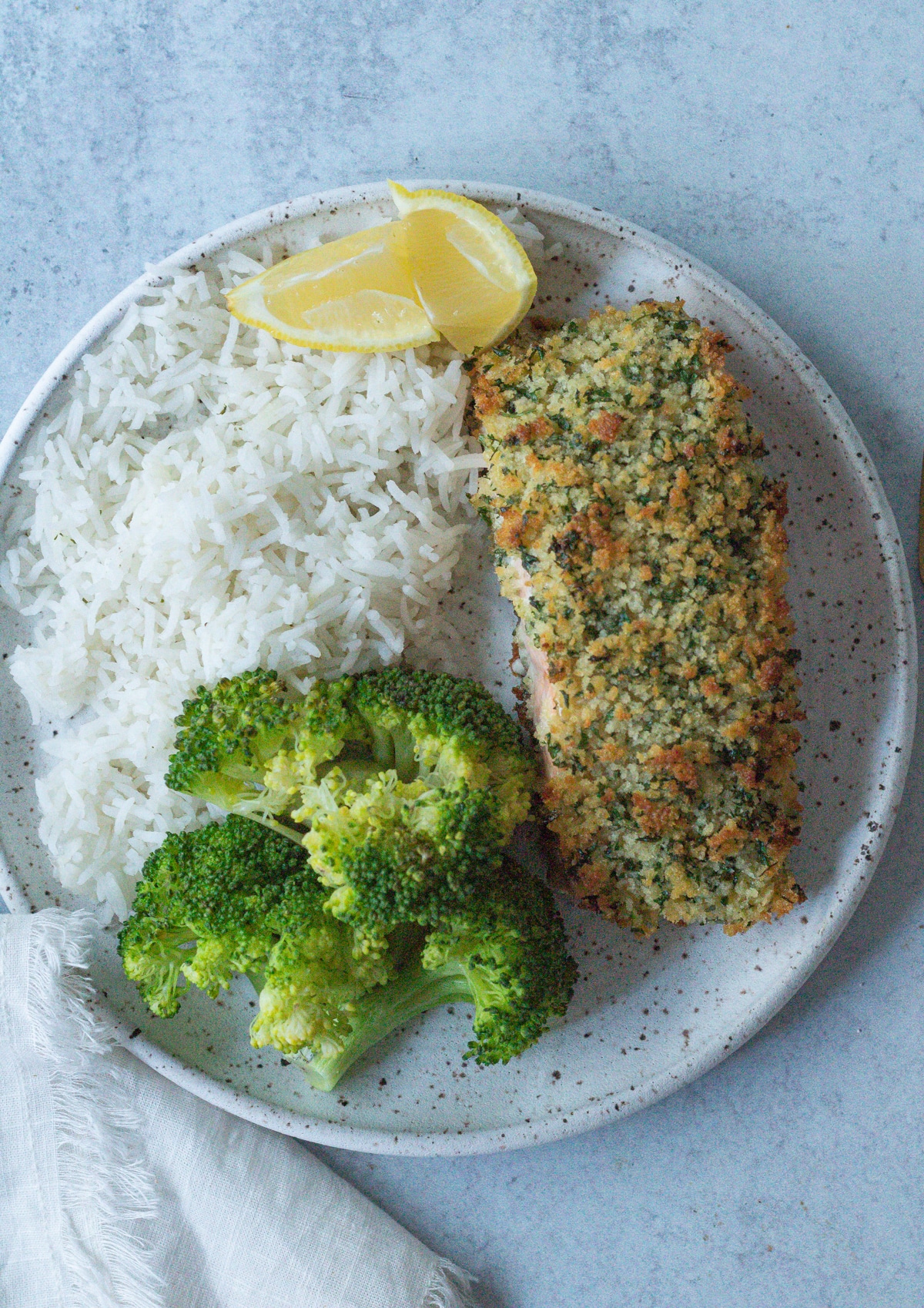 dinner plate with crispy baked herb crusted salmon, rice and broccoli.