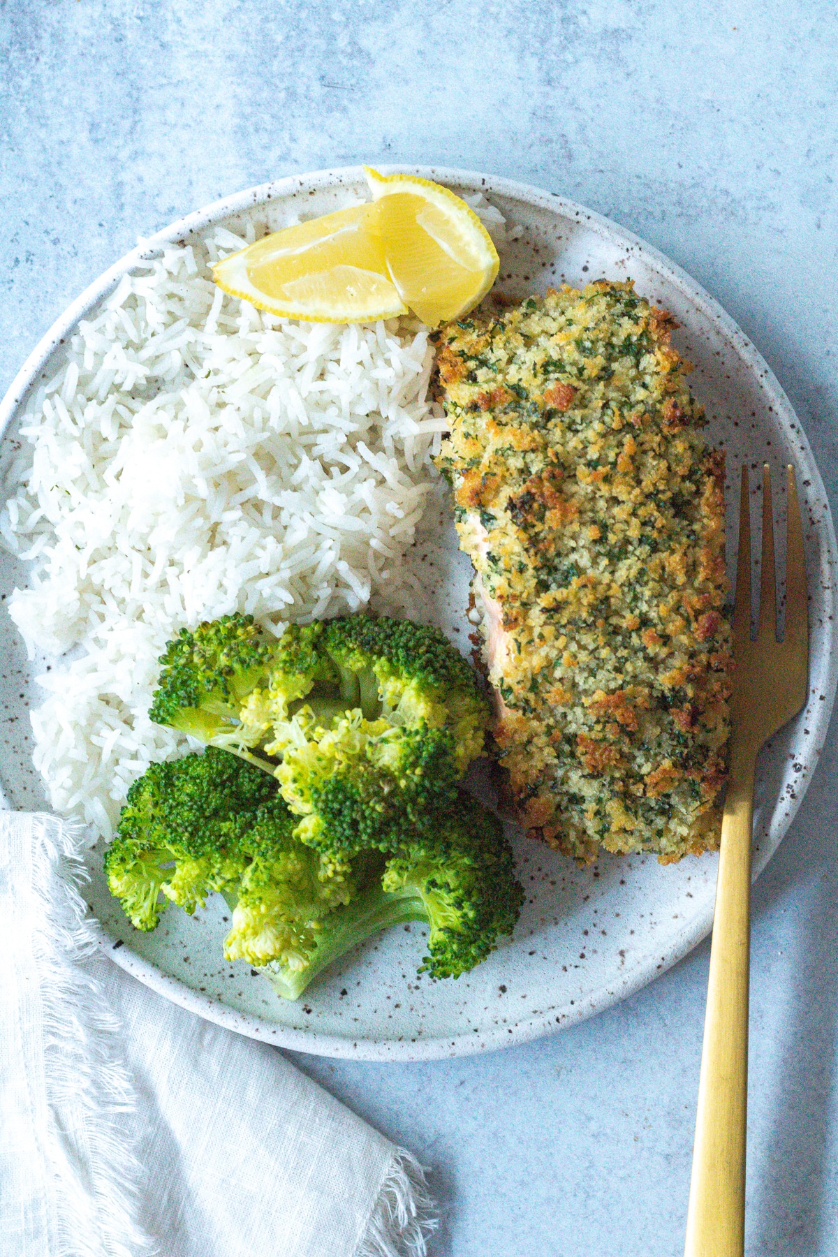 plate with crispy baked herb crusted salmon, rice and steamed broccoli.