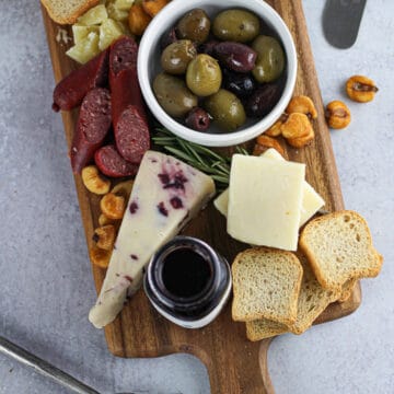 simple cheese board for two with cheese, meats, small spoon on side