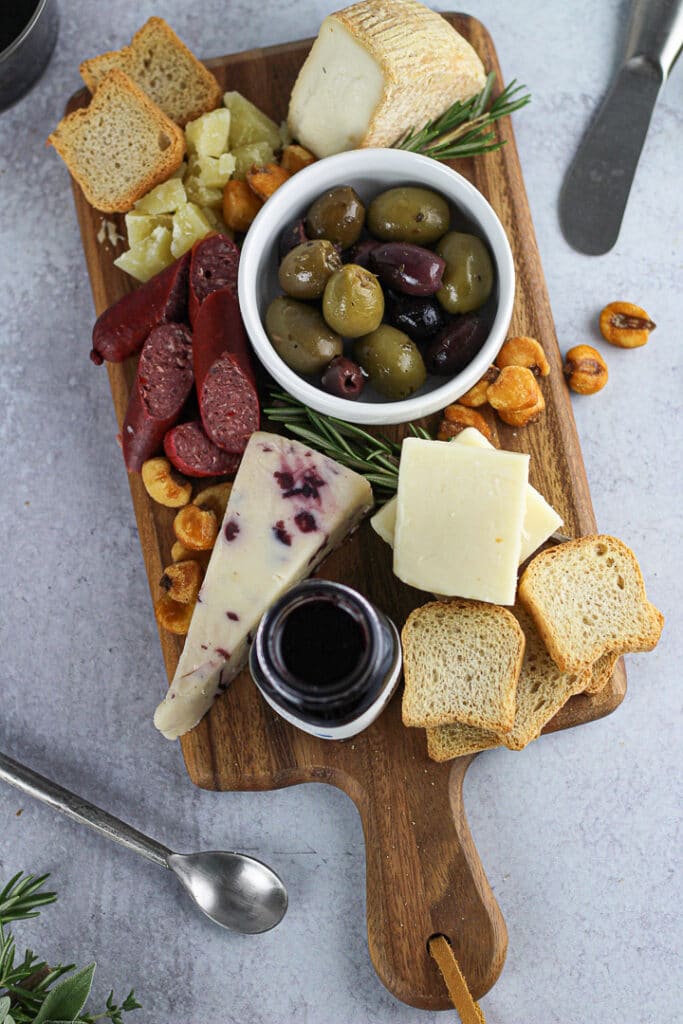 small cheese board with cheese, meats, small spoon on side