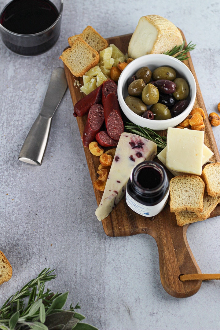 final simple cheese board for two with wine glass and cheese knife.