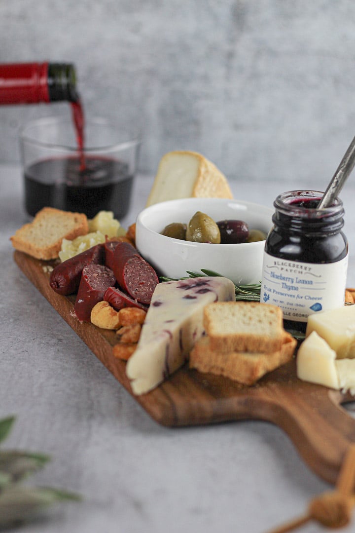 pouring wine next to simple cheese board for two.