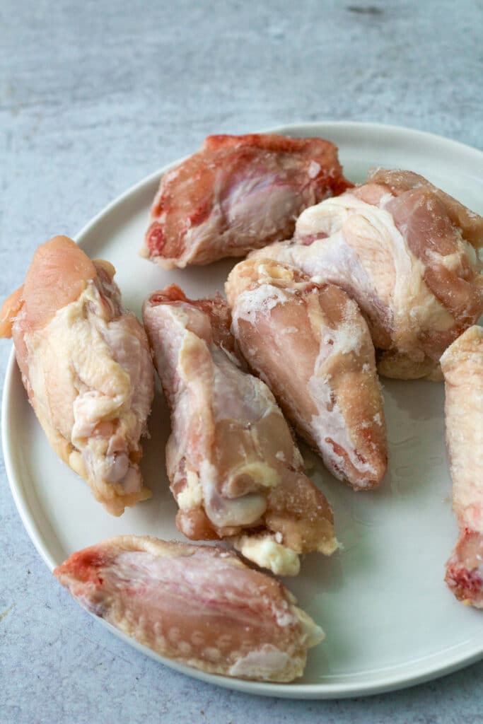 Raw frozen chicken wings on plate.