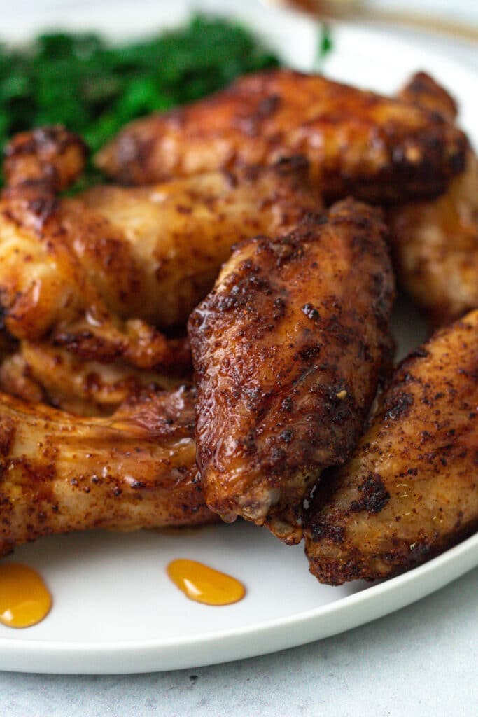 Spiced chicken wings on plate with hot honey drizzle.