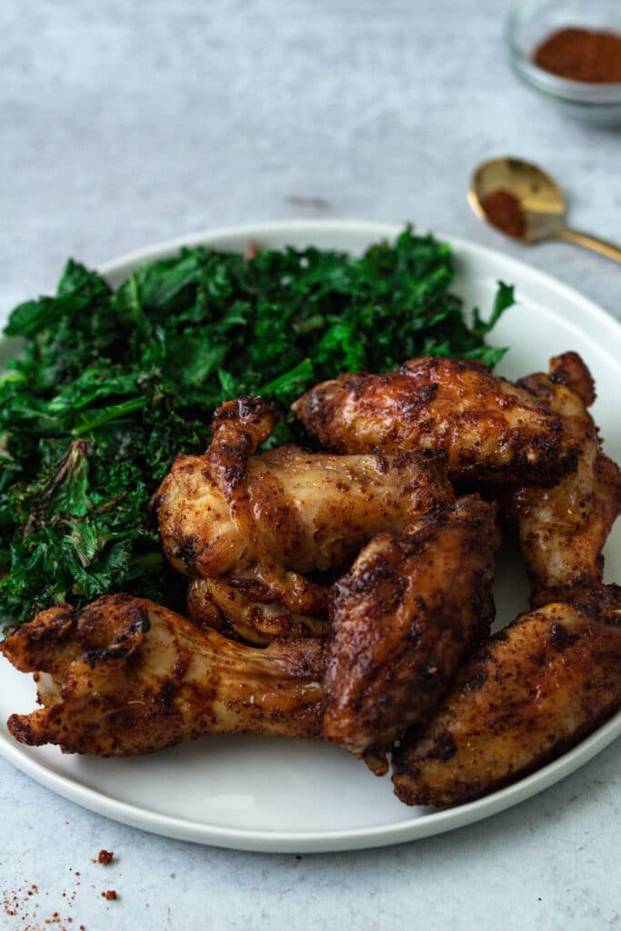 Plate of chicken wings and sauteed kale.